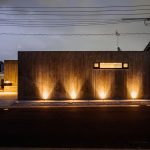 温かみのあるオレンジ色の光が照らす、コンクリート住宅の夜間の外観